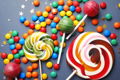 Photo of Lollipops and colorful candies on grey background, top view