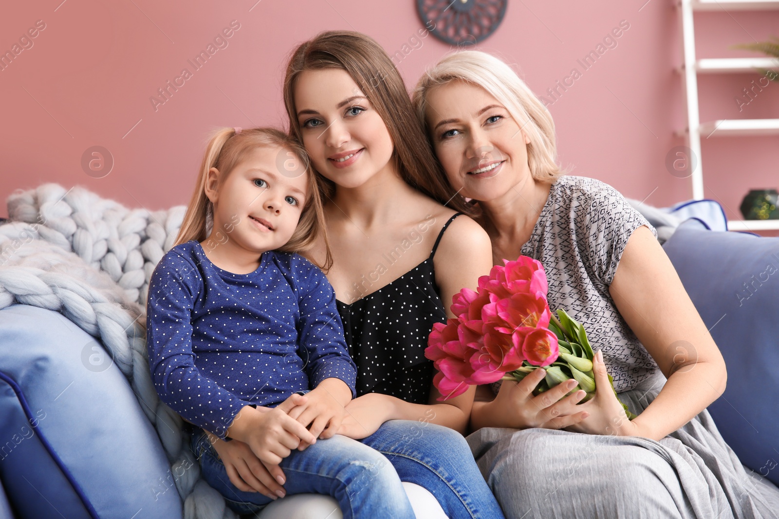 Photo of Happy young woman with her mother and daughter at home