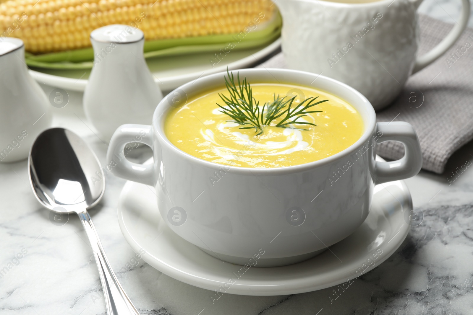 Photo of Delicious creamy corn soup served on white marble table