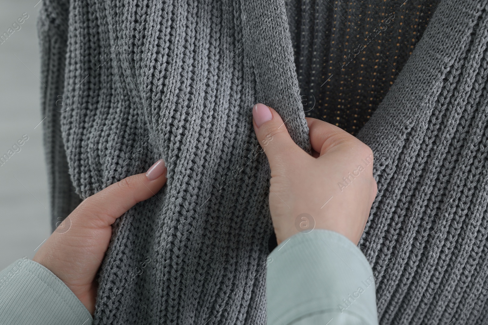 Photo of Woman touching clothes made of soft knitted fabric, closeup