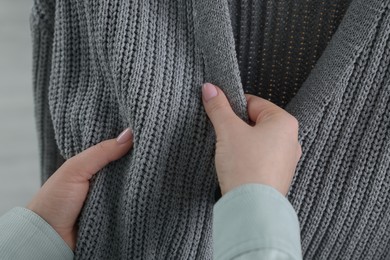 Photo of Woman touching clothes made of soft knitted fabric, closeup