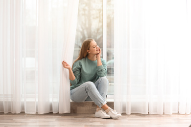 Photo of Beautiful young woman near window at home