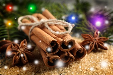 Different spices and fir tree branches on brown sugar, closeup. Cinnamon, anise, brown sugar