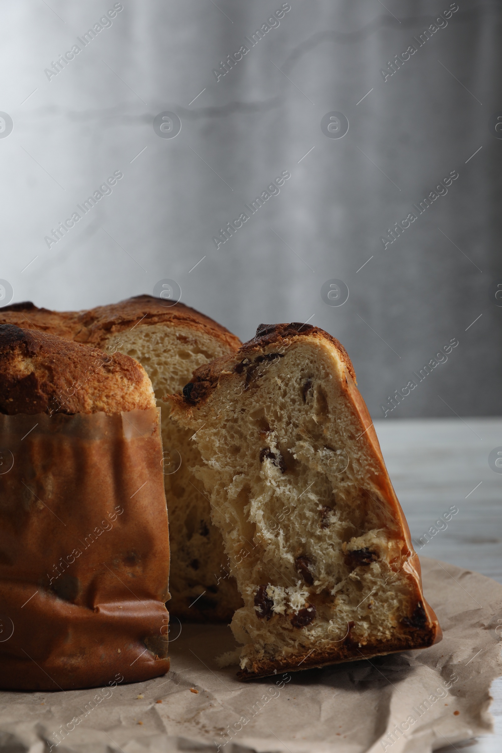 Photo of Delicious cut Panettone cake with raisins on white wooden table, closeup. Traditional Italian pastry