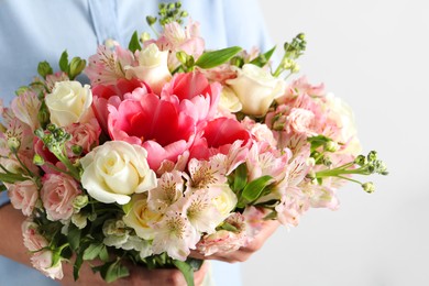 Woman with beautiful bouquet of fresh flowers on light background, closeup