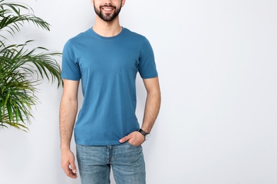 Photo of Young man in t-shirt near light wall, closeup. Mock up for design