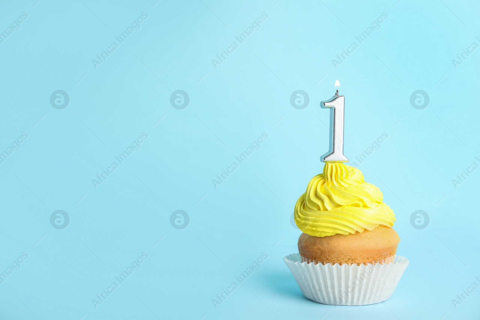 Photo of Birthday cupcake with number one candle on blue background, space for text