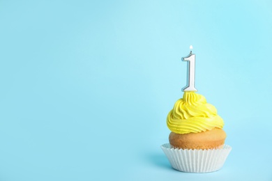 Photo of Birthday cupcake with number one candle on blue background, space for text