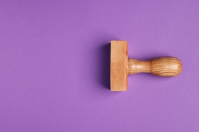 Photo of One wooden stamp tool on purple background, top view. Space for text