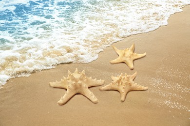 Beautiful waves and sea stars on sandy beach