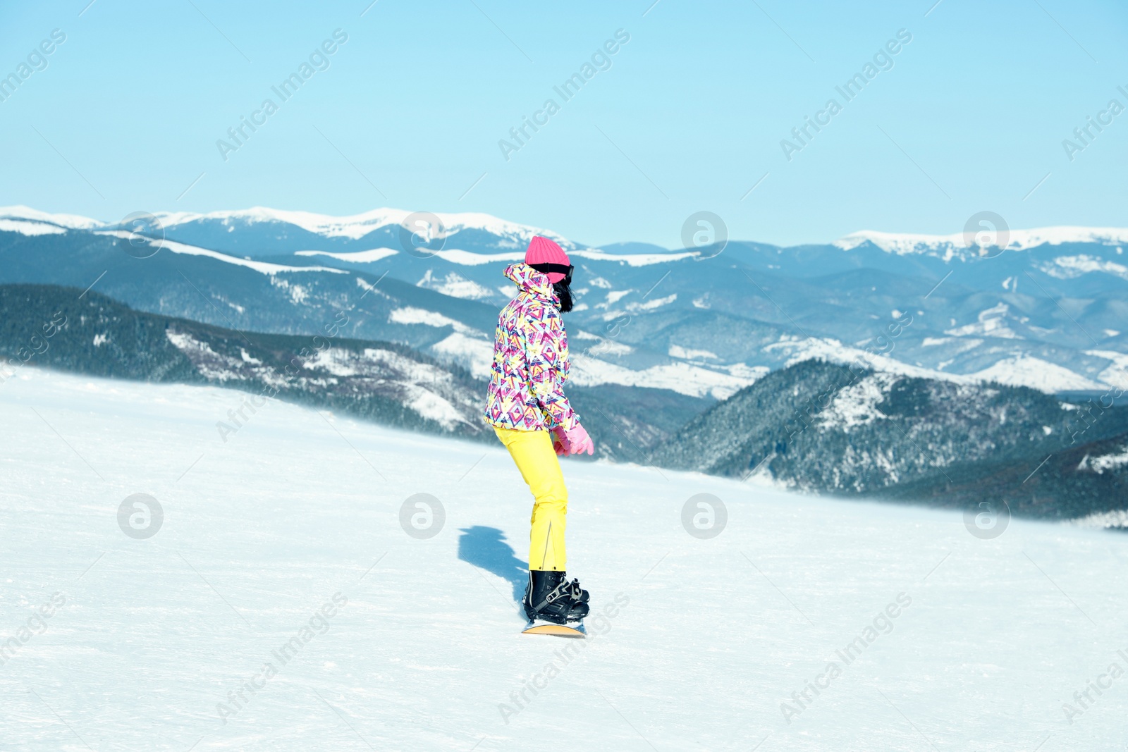 Photo of Female snowboarder on snowy slope in mountains. Winter vacation
