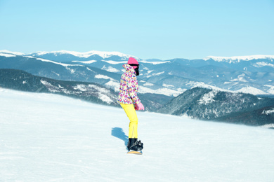 Photo of Female snowboarder on snowy slope in mountains. Winter vacation
