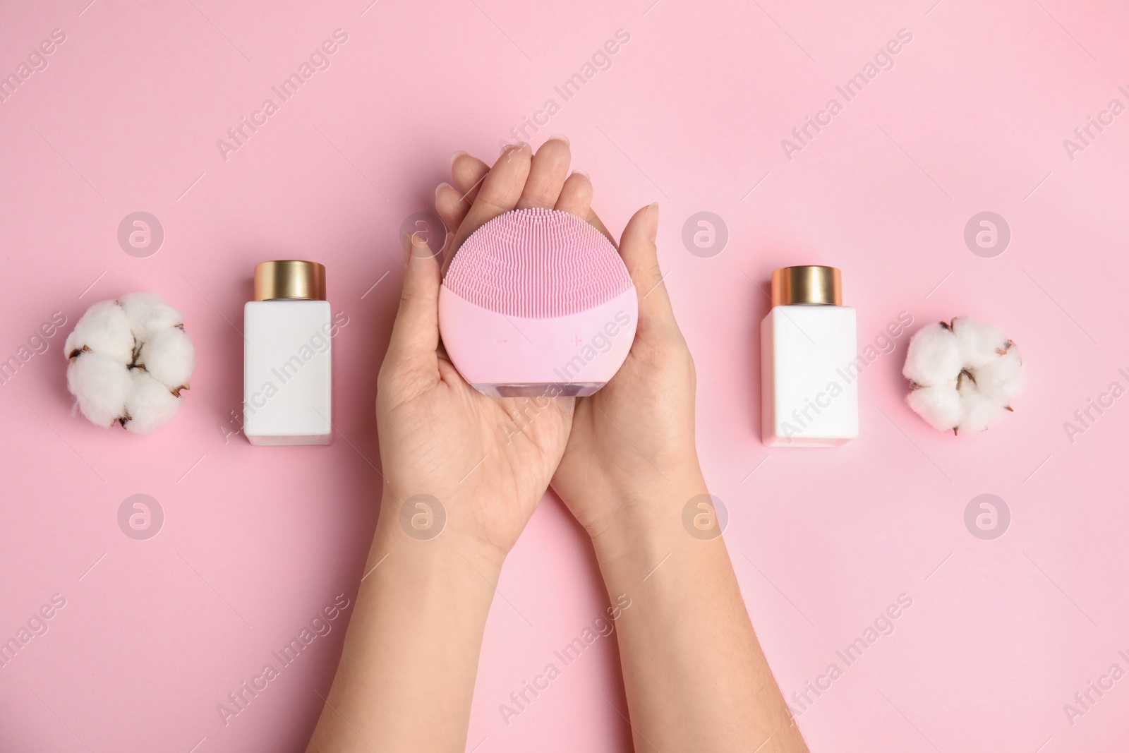 Photo of Woman with face cleansing brush on pink background, top view. Cosmetic accessory