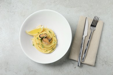Photo of Tasty capellini with mussels and lemon served on light grey table, flat lay. Exquisite presentation of pasta dish