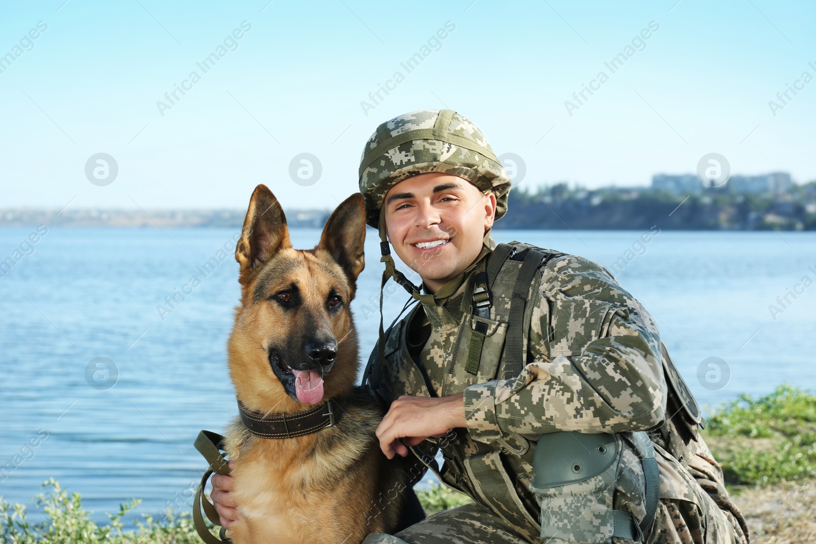 Photo of Man in military uniform with German shepherd dog near river