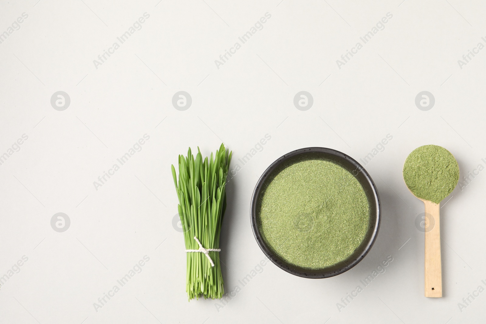 Photo of Wheat grass powder and fresh green sprouts on light table, flat lay. Space for text