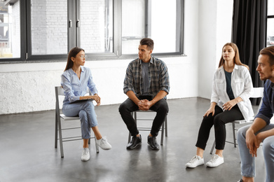 Psychotherapist working with patients in group therapy session indoors