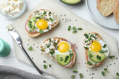 Photo of Delicious sandwiches with egg, cheese, avocado and microgreens on white wooden table, flat lay