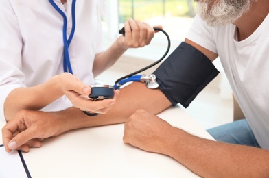 Doctor checking senior man's pulse in hospital