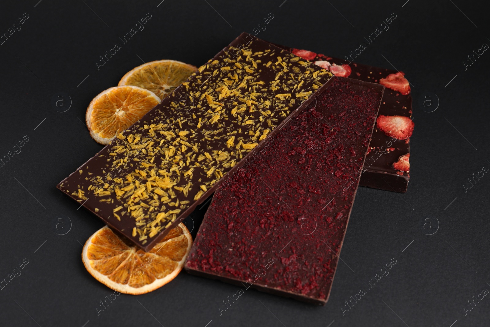 Photo of Chocolate bars with freeze dried fruits on black background