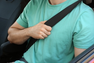 Photo of Man with fastened safety belt on driver's seat in car, closeup