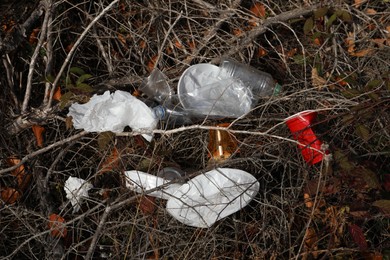 Photo of Different plastic garbage stuck between bush branches