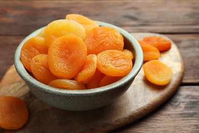 Bowl of tasty apricots on wooden table, closeup. Dried fruits