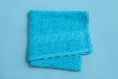 Photo of Folded soft beach towel on light blue background, top view
