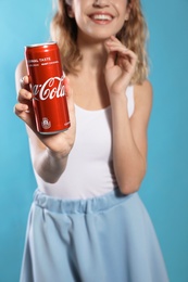 Photo of MYKOLAIV, UKRAINE - NOVEMBER 28, 2018: Young woman with Coca-Cola can on color background