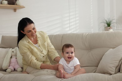 Happy mother with her cute baby on sofa at home