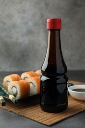 Tasty soy sauce and sushi rolls with salmon on grey table