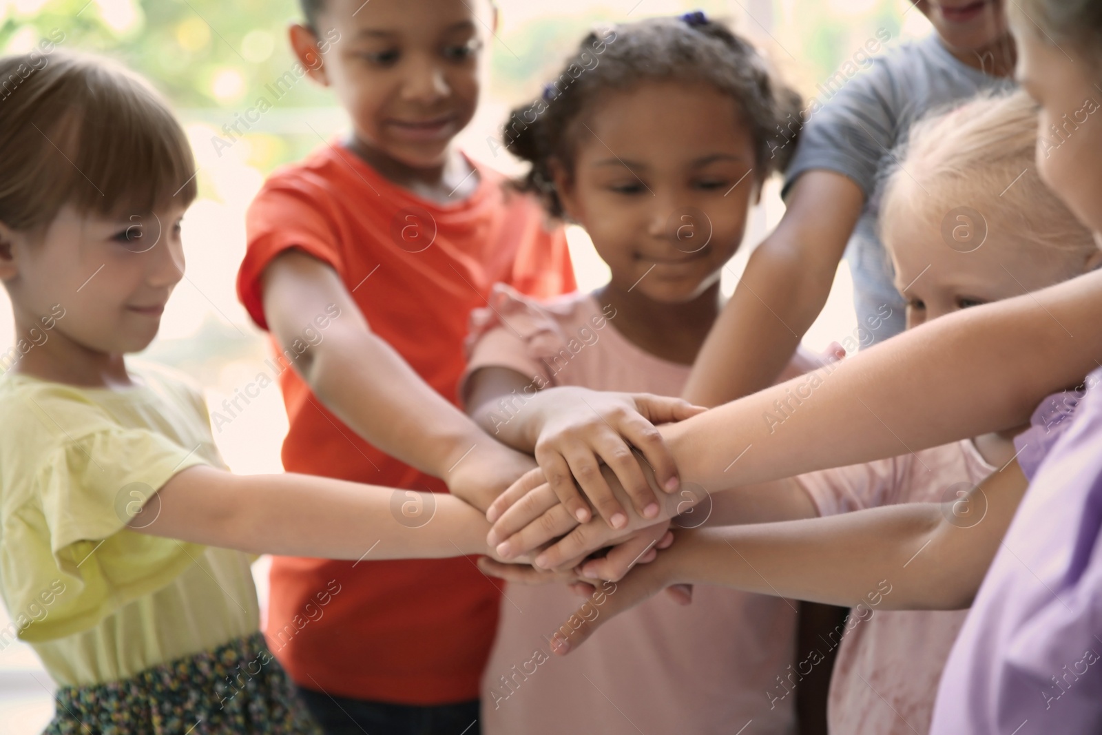 Photo of Little children putting their hands together, indoors. Unity concept