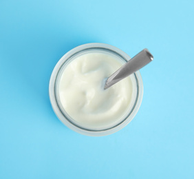 Tasty organic yogurt on light blue background, top view