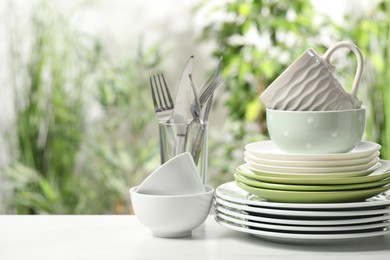 Photo of Beautiful ceramic dishware, cutlery and cup on white table outdoors, space for text