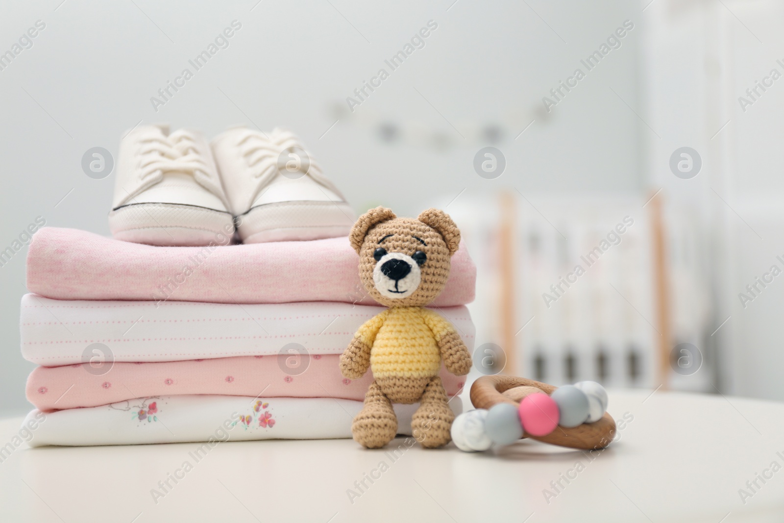 Photo of Stack of baby clothes, shoes and accessories on white table indoors