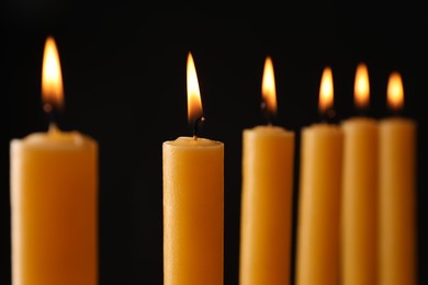 Photo of Many burning church candles on black background, closeup
