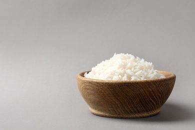 Bowl of tasty cooked rice on grey background. Space for text