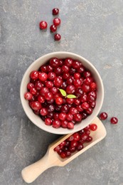 Photo of Fresh ripe cranberries in bowl and scoop on grey table, flat lay