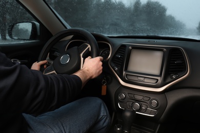 Photo of Young man driving car along winter forest, closeup