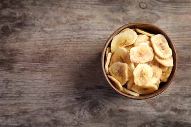 Photo of Bowl with sweet banana slices on wooden  table, space for text. Dried fruit as healthy snack