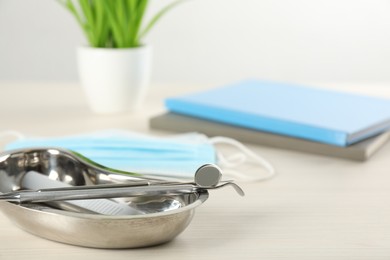 Kidney shaped tray with set of dentist's tools on wooden table, closeup. Space for text
