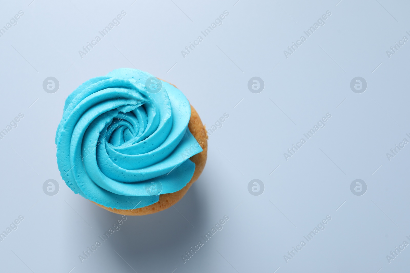 Photo of Delicious cupcake with bright cream on light background, top view. Space for text