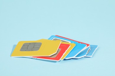 Photo of Different SIM cards on light blue background, closeup