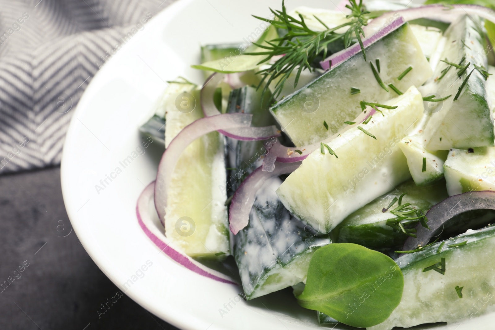 Photo of Plate with creamy cucumber salad on table, closeup