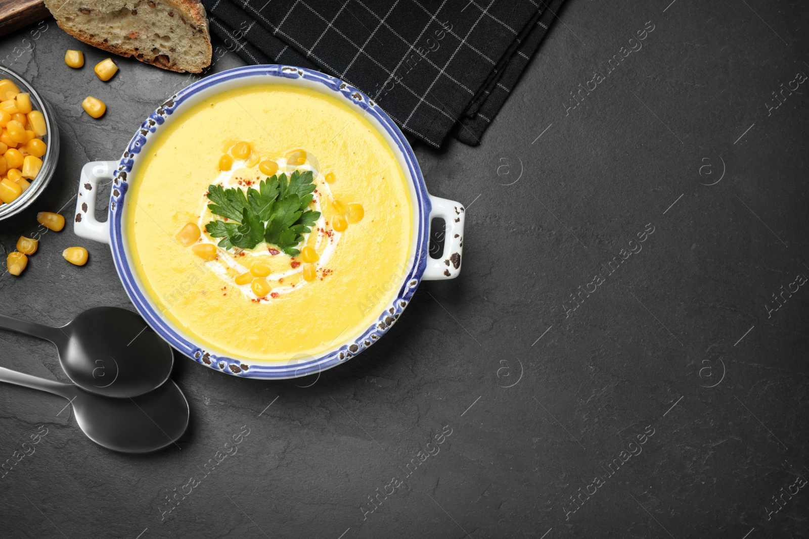 Photo of Delicious creamy corn soup served on black table, flat lay. Space for text