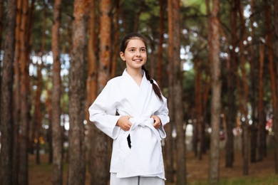 Cute little girl in kimono in forest. Karate practicing
