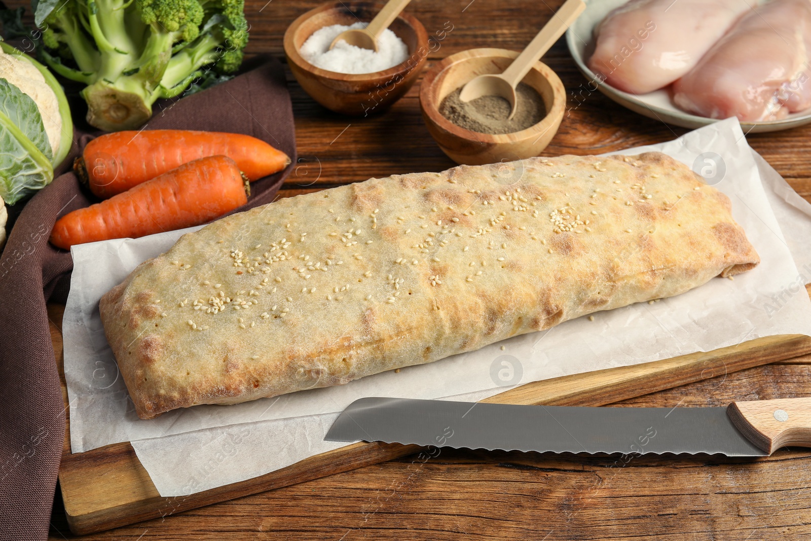 Photo of Delicious strudel with chicken and vegetables on wooden table
