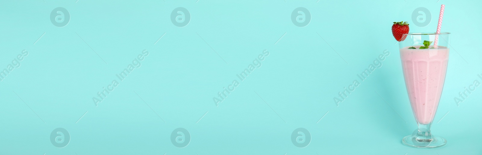 Photo of Tasty fresh milk shake with strawberry on light blue background. Space for text