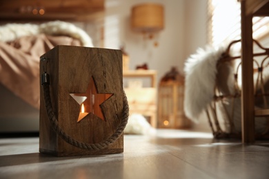 Photo of Decorative wooden lantern with burning candle in cozy bedroom, space for text. Interior element