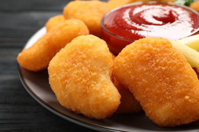 Photo of Tasty fried chicken nuggets served on black wooden table, closeup
